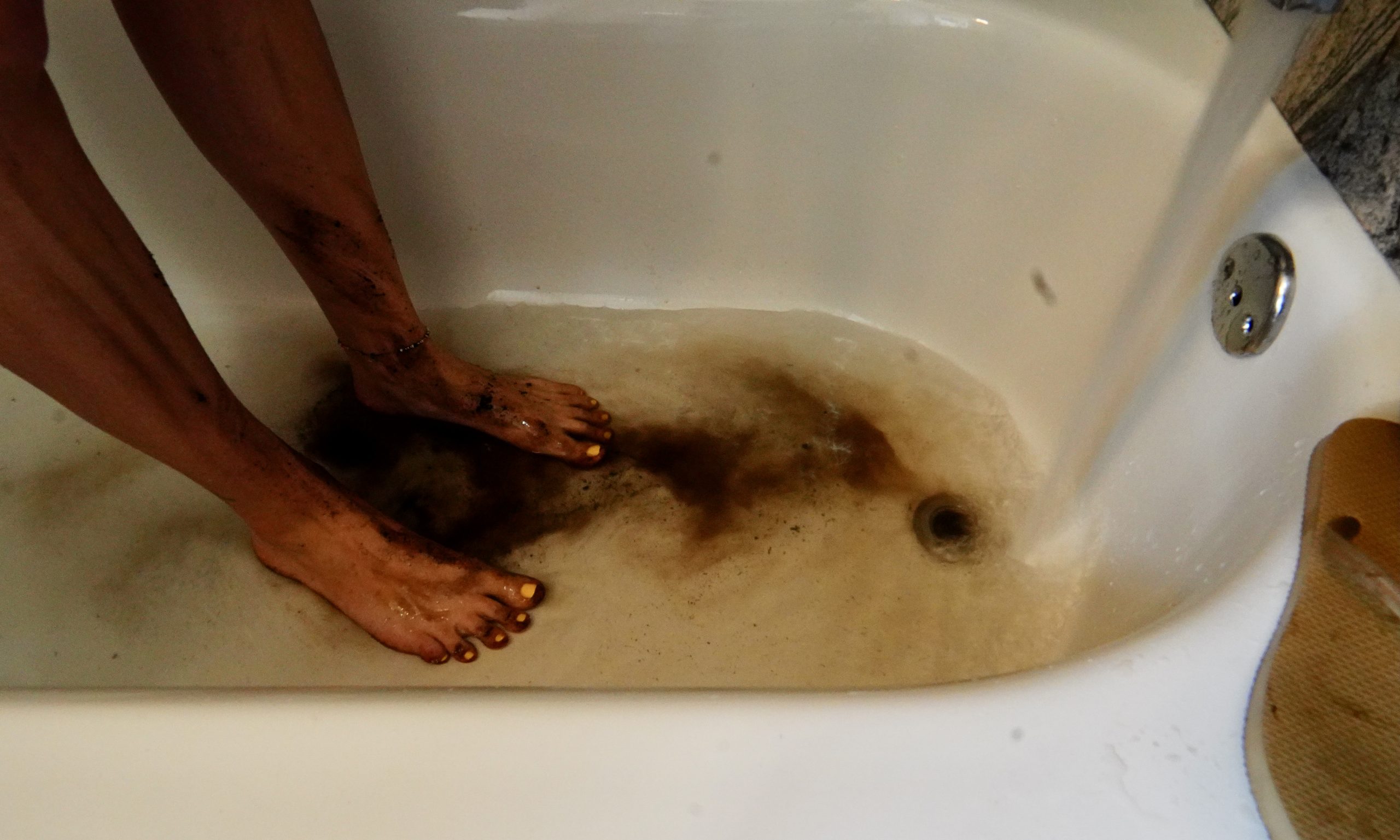 feet in bathtub with water running and soil washing off